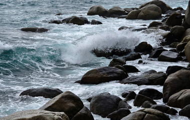 The powerful waves are forcefully crashing against the rocks in the vast ocean