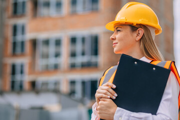 Female construction worker holding clipboard at a building site