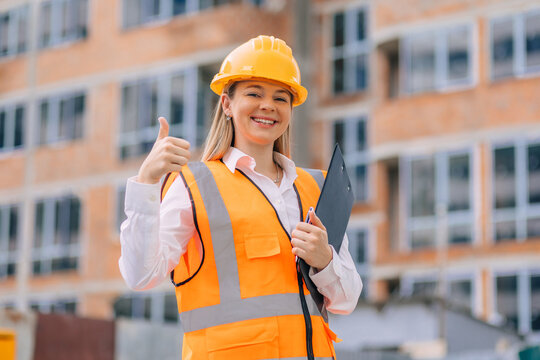 Female construction worker giving a thumbs up on building site - Powered by Adobe