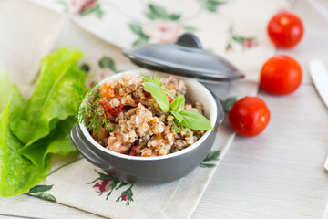 boiled buckwheat with vegetables in a ceramic bowl on a wooden table