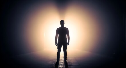 Man standing in dramatic light, illuminated by a powerful spotlight from behind, creating a striking silhouette
