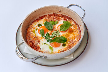A Delicious Serving of Shakshuka with Poached Eggs, Fresh Herbs, and a Rich Tomato Sauce in a Le Creuset Dish Perfect for Brunch