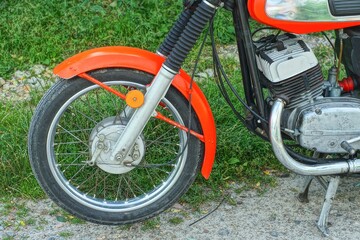 front wheel with black rubber tire and spokes with fork and part of industrial iron powerful engine...