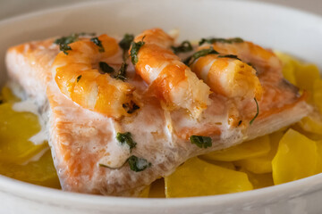 Salmon fillet cooked with shrimps and potatoes, creating a healthy and delicious seafood meal rich in omega-3 fatty acids, proteins, vitamins, and nutrients