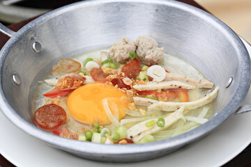Breakfast with fried eggs in a pan with bacon and vegetables on dark background, top view