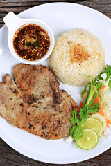 Pan-fried Pork Neck with Spicy Dipping Sauce Serve with Garlic Fried Rice on old wooden backdrop