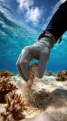A close-up of a scuba diver gloved hand touching the fine sandy seabed underwater