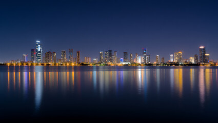Illuminated city skyline reflected on calm water at night cityscape urban
