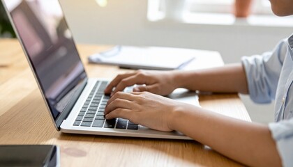 Fototapeta premium Hands typing on a laptop keyboard at a desk, illustrating digital work and focus