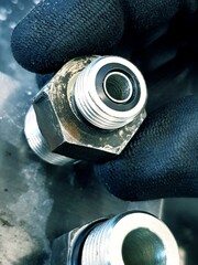 Close up of a nut and bolt in a car mechanic's hand