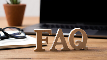 Wooden letters spelling frequently asked questions on desk laptop glasses