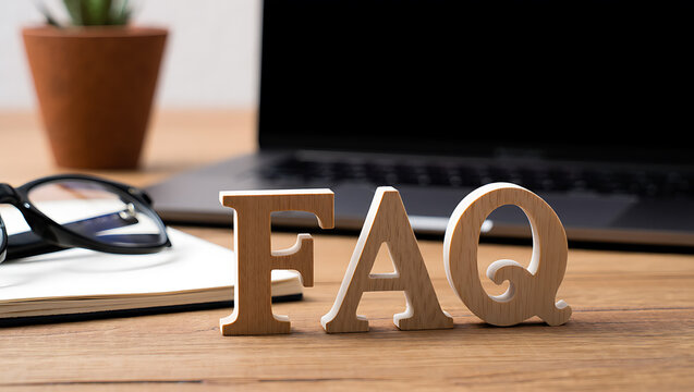 Wooden letters spelling frequently asked questions on desk laptop glasses