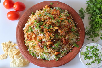 Chicken biryani served on a plate, topped with fried onions, cashews, raisins, and cilantro