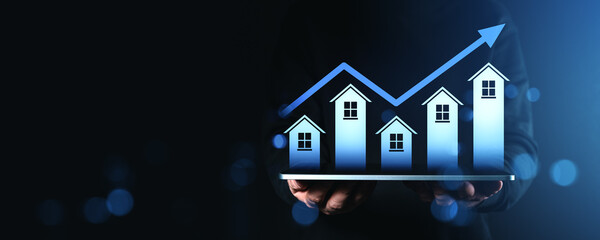 Real estate growth concept with increasing house chart and upward arrow held by hands on dark blue gradient background with futuristic effect.