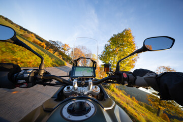 Driver riding motorcycle on empty road during sunset , view from the handlebars