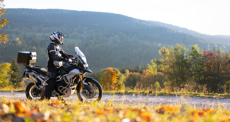 Driver posing on motorcycle during sunrise, rural countryside