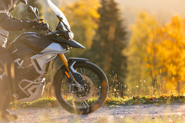 Driver posing on motorcycle during sunrise, rural countryside