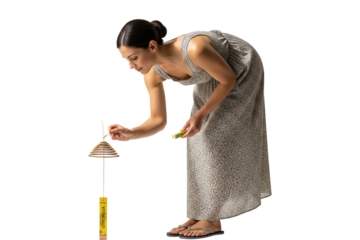 Woman lighting a citronella mosquito coil outdoors.