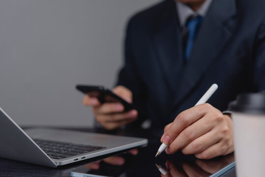Communication and business technology. A businessman uses a digital tablet with a stylus pen for online work, with a laptop and smartphone on the side, online meetings, or electronic business.