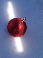 Red ball with glitter on it is sitting on a snowy surface