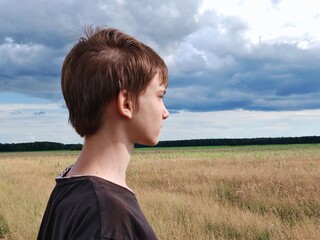 thoughtful teenager stands quietly in a serene field, deep in thought amidst the wilderness. Portrait of a face in profile thoughtful teenage boy