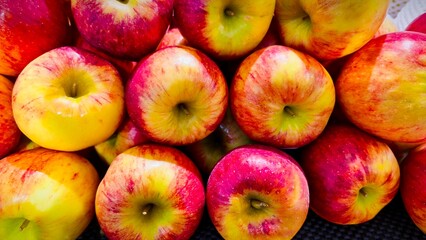Shiny red and yellow apples displayed in a vibrant and colorful fruit pile.