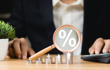Coins moneys stacked and have magnifying glass with graph and percentage symbol inside. Finance and...