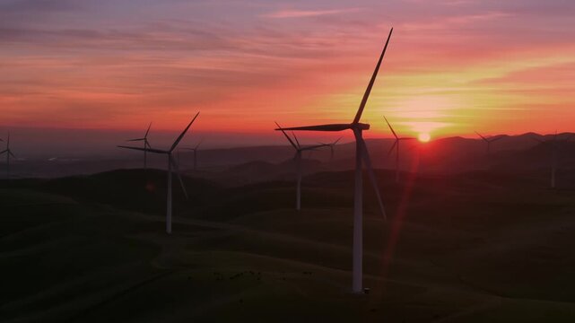 Wind turbines stand tall on rolling hills in Altamont Pass, Livermore, California, USA, at sunset. They generate clean, renewable energy, contributing to a sustainable future.