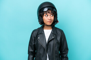 Young Argentinian woman with a motorcycle helmet isolated on blue background and looking up
