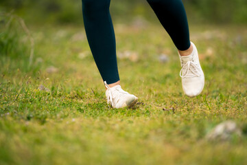 Woman spraining ankle while running outdoors, wear outfit leggings and white sneakers, close-up of...