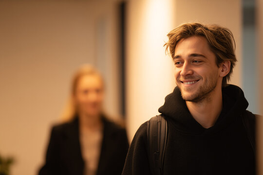 Smiling Man in Motion: Capturing a candid moment, a smiling individual, backpack slung over his shoulder, strolls through a well-lit interior, radiating approachability and positivity.