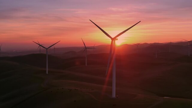 Wind turbines stand tall on rolling hills in Altamont Pass, Livermore, California, USA, at sunset. They generate clean, renewable energy, contributing to a sustainable future.