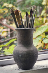 Various professional paint brushes in the clay jar, selective focus