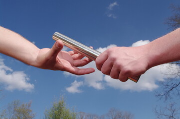 Two people are holding a baton and one is handing it to the other
