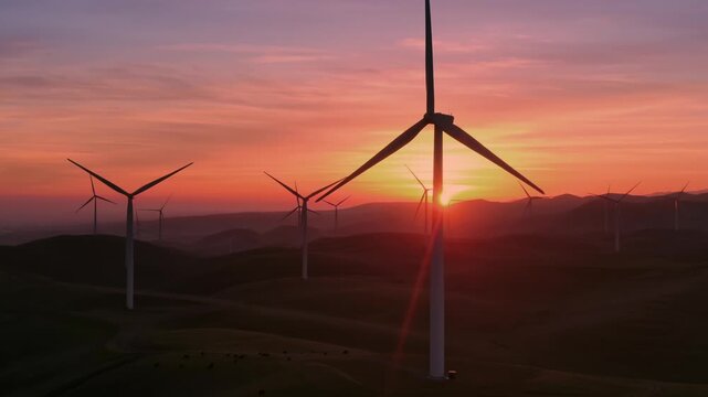 Wind turbines stand tall on rolling hills in Altamont Pass, Livermore, California, USA, at sunset. They generate clean, renewable energy, contributing to a sustainable future.