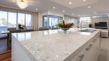 Modern kitchen island with polished white quartz countertop, overlooking a dining area and city views