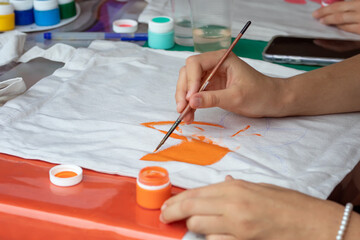 woman hands decorating fabric using paint. painting with brush on textile. Close up of