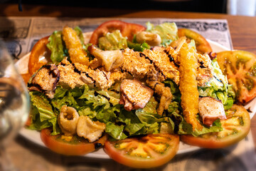 Gourmet seafood salad with grilled octopus, fried shrimp, lettuce, tomato slices and balsamic