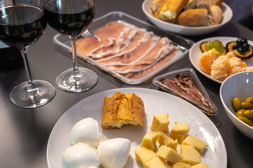 Appetizer table with red wine, mozzarella, hard cheese, prosciutto, anchovies, bread, olives