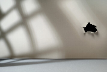 Sunlight from the window shines on the empty broken room wall with hole
