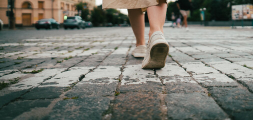 Girl is walking in a city, female legs in shoes closeup.