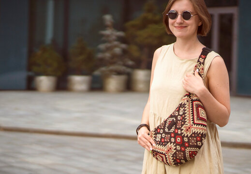 A girl in sunglasses with a smiley face walks around the city.