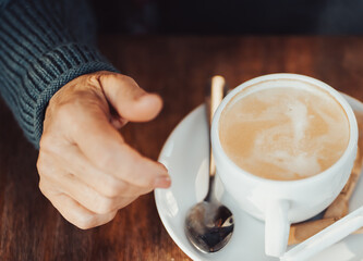 An elderly woman drinks hot coffee, hand and a cup closeup.