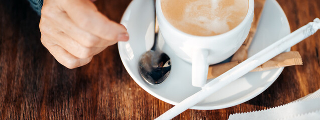 An elderly woman drinks hot coffee, hand and a cup closeup.