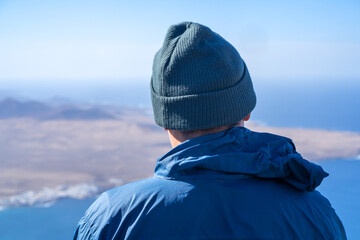 A man in a hat is looking on a beautiful landscape with ocean. © Zhanna