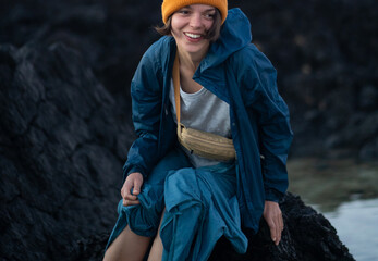 A girl enjoys a beautiful beach with black volcanic lava formations on the Canary islands.