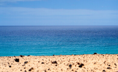 A sandy beach on the coastline of the ocean with clear blue water.