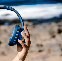 A girl holds a wireless headphones in hands, closeup view.