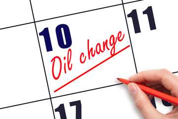10th day of the month.  Hand writing Oil change reminder and drawing a line on calendar with red pen on white background. Vehicle maintenance reminder. Planning and scheduling