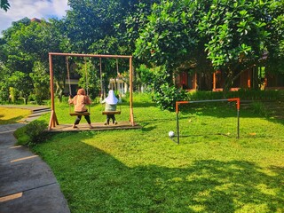 Girls on swings near a small soccer goal